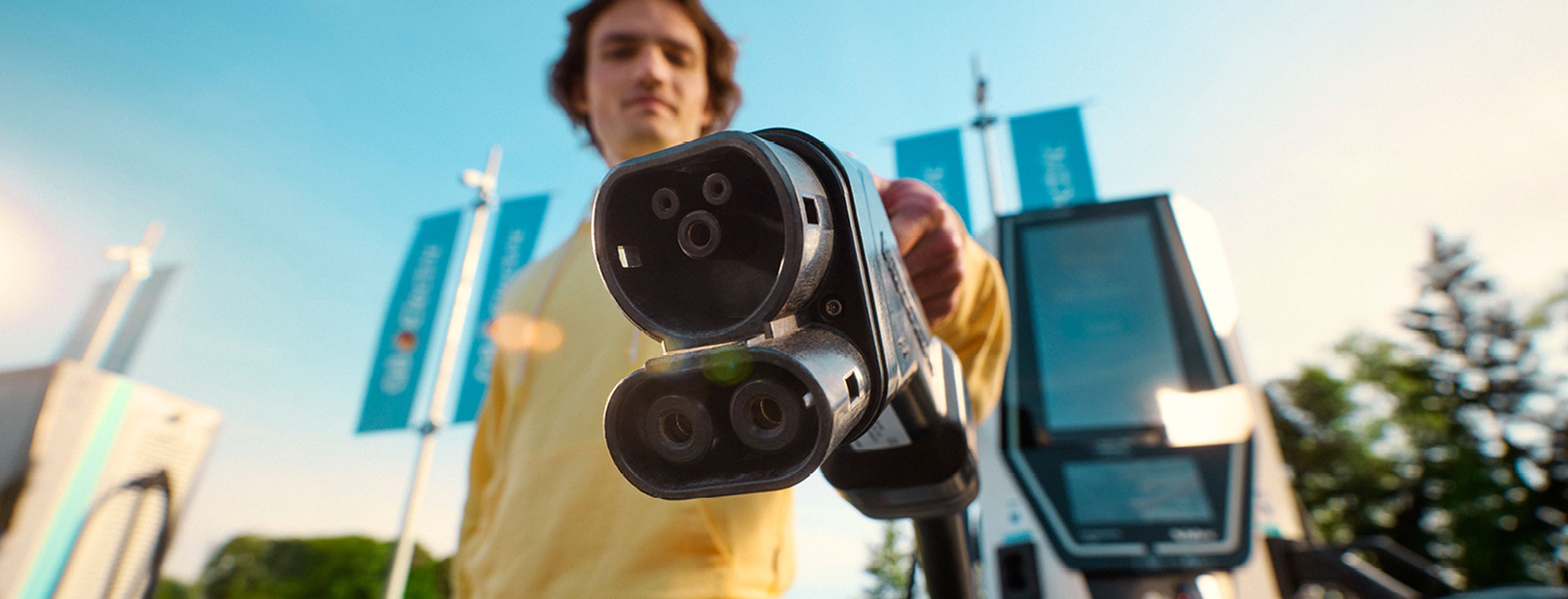Homme montre une prise de recharge Q8 Electric à la caméra.