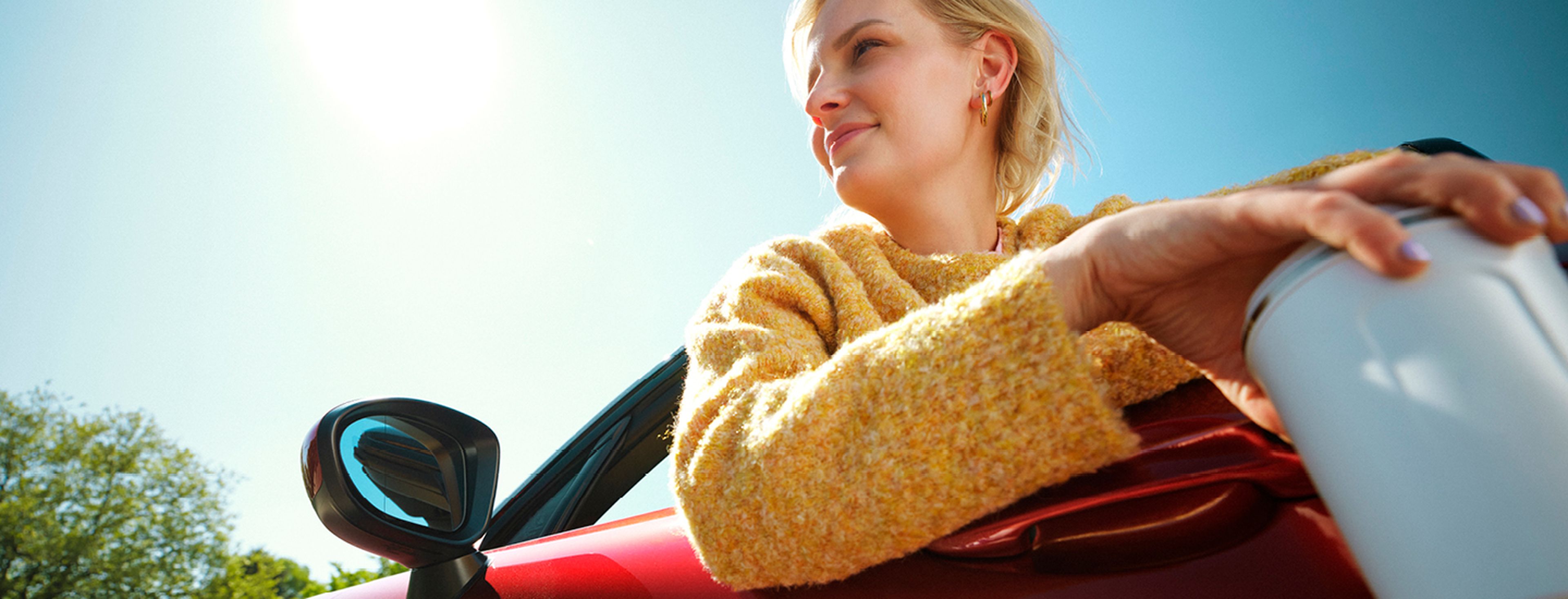 Femme en cabriolet rouge avec tasse de café chez Q8.