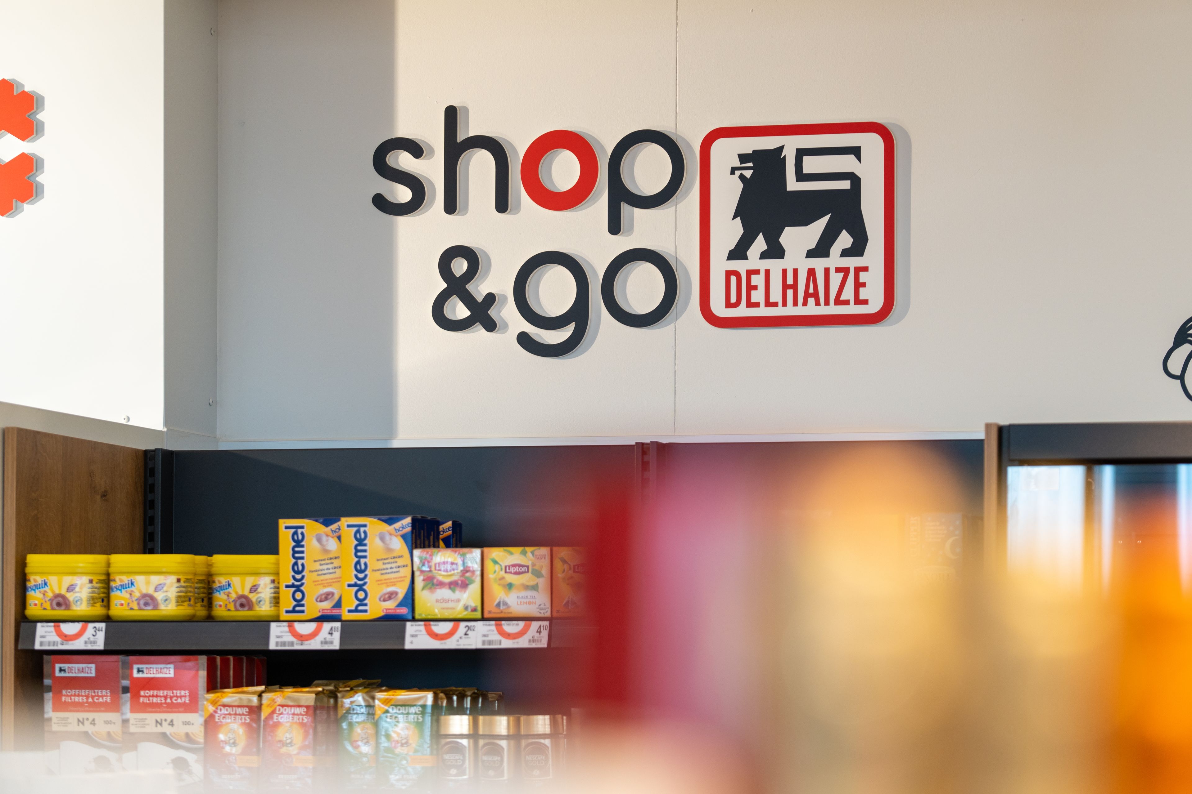 Vue intérieure d’un shop&go Delhaize chez Q8, avec le logo Delhaize visible sur le mur.