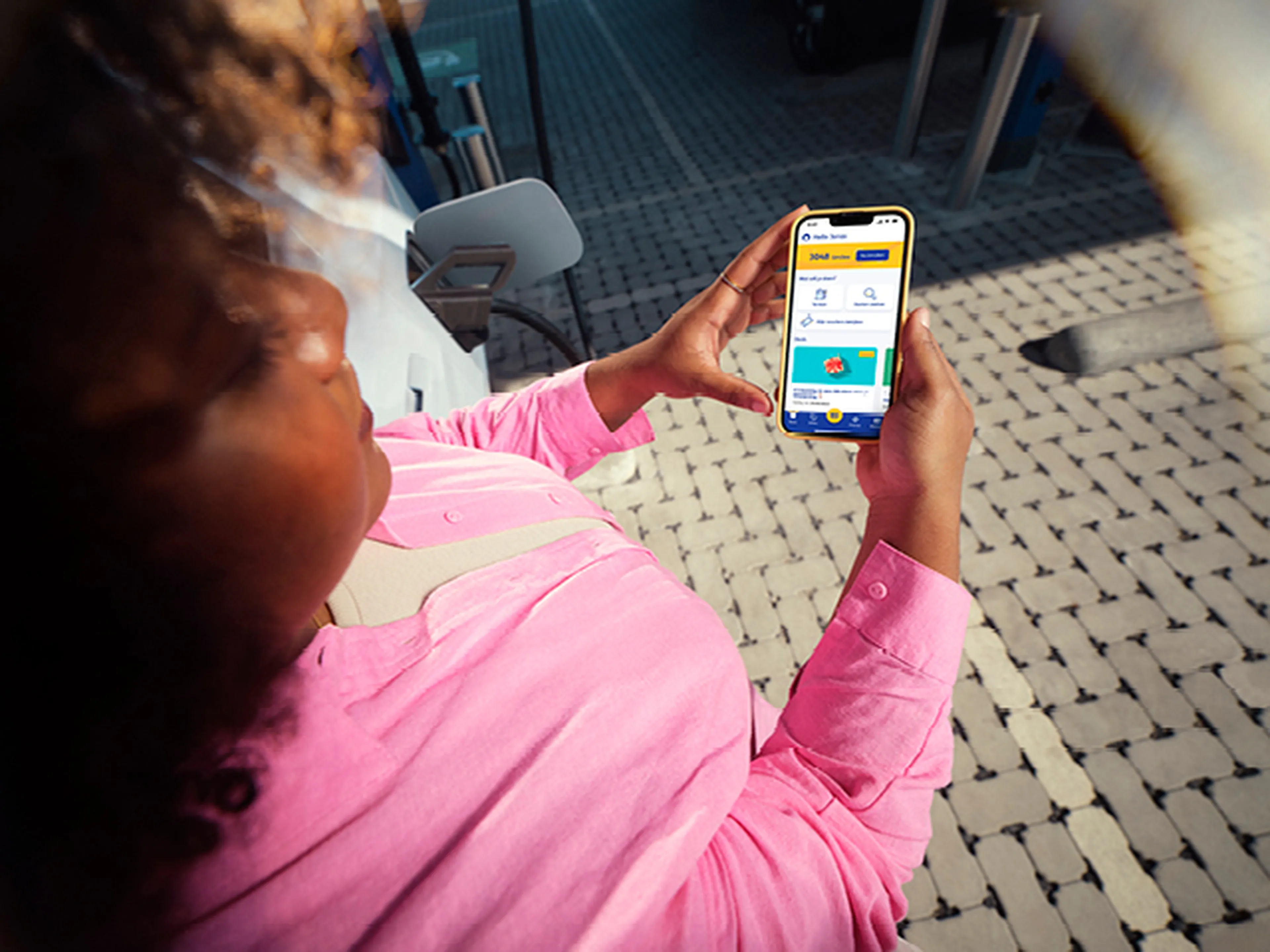 Une femme consulte l'application professionnelle Q8 à une station Q8