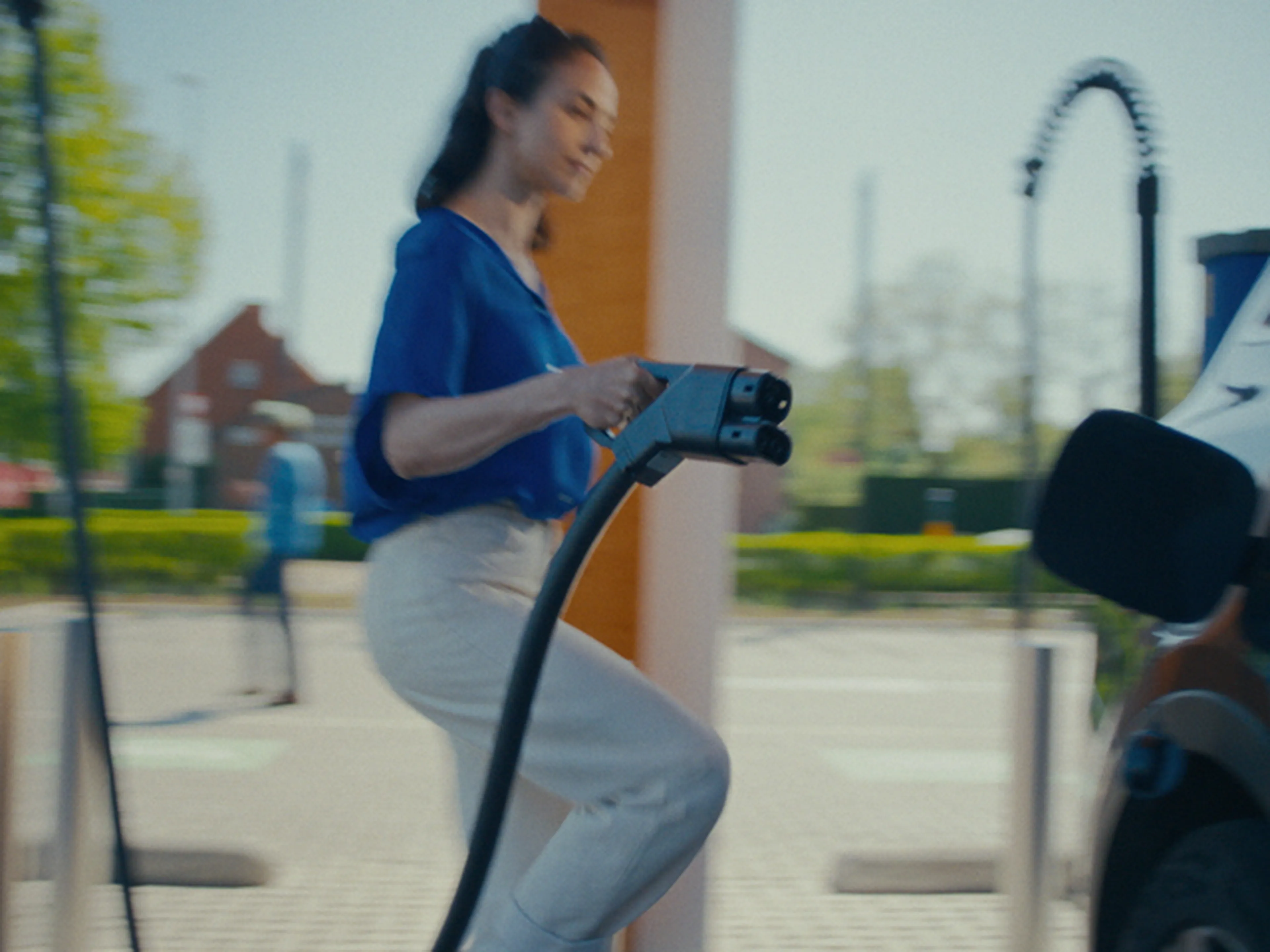 Une femme recharge sa voiture électrique chez Q8.