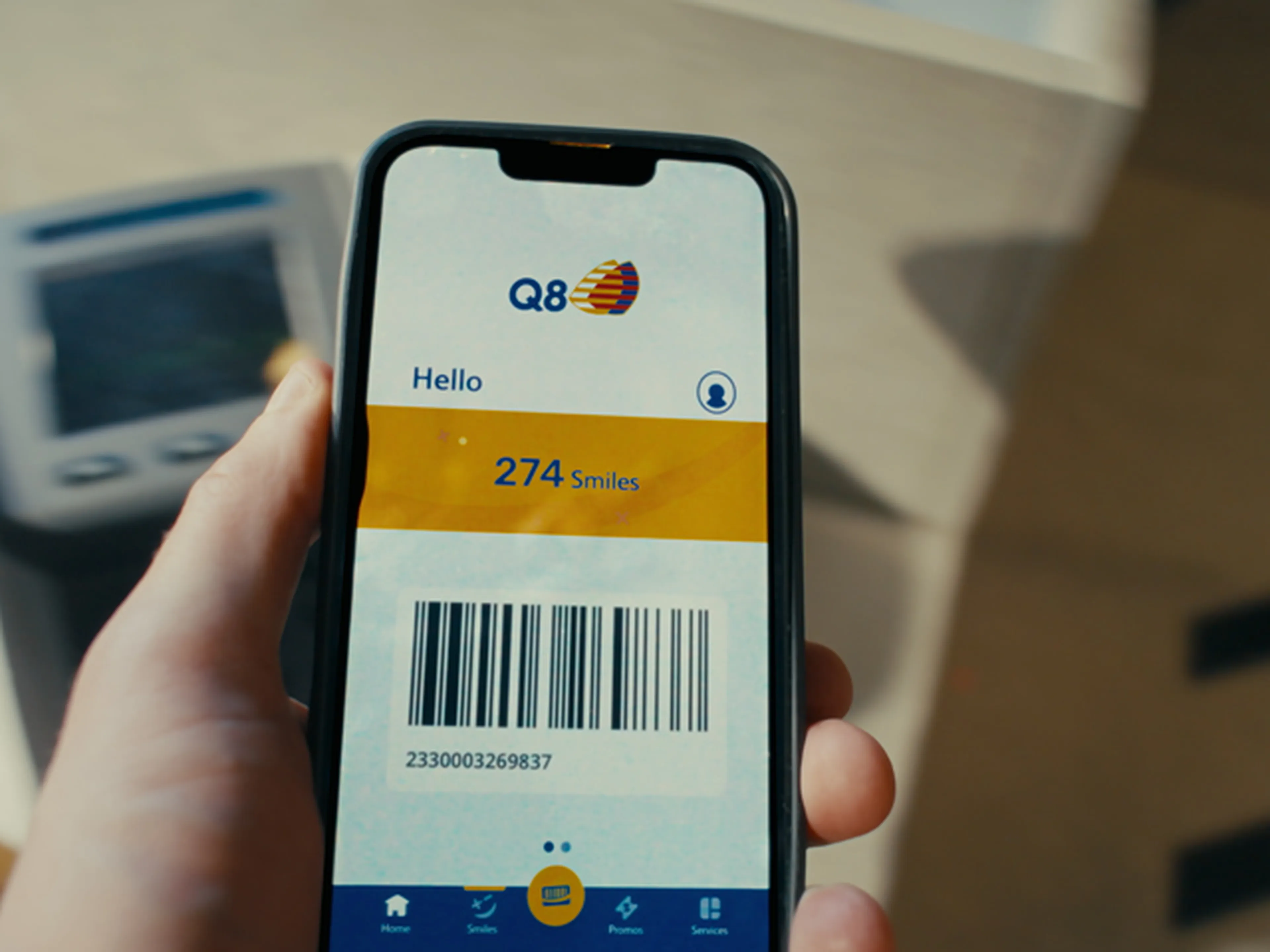 L'application Q8 avec les points Smiles et le code-barres est affiché pour payer à la caisse.