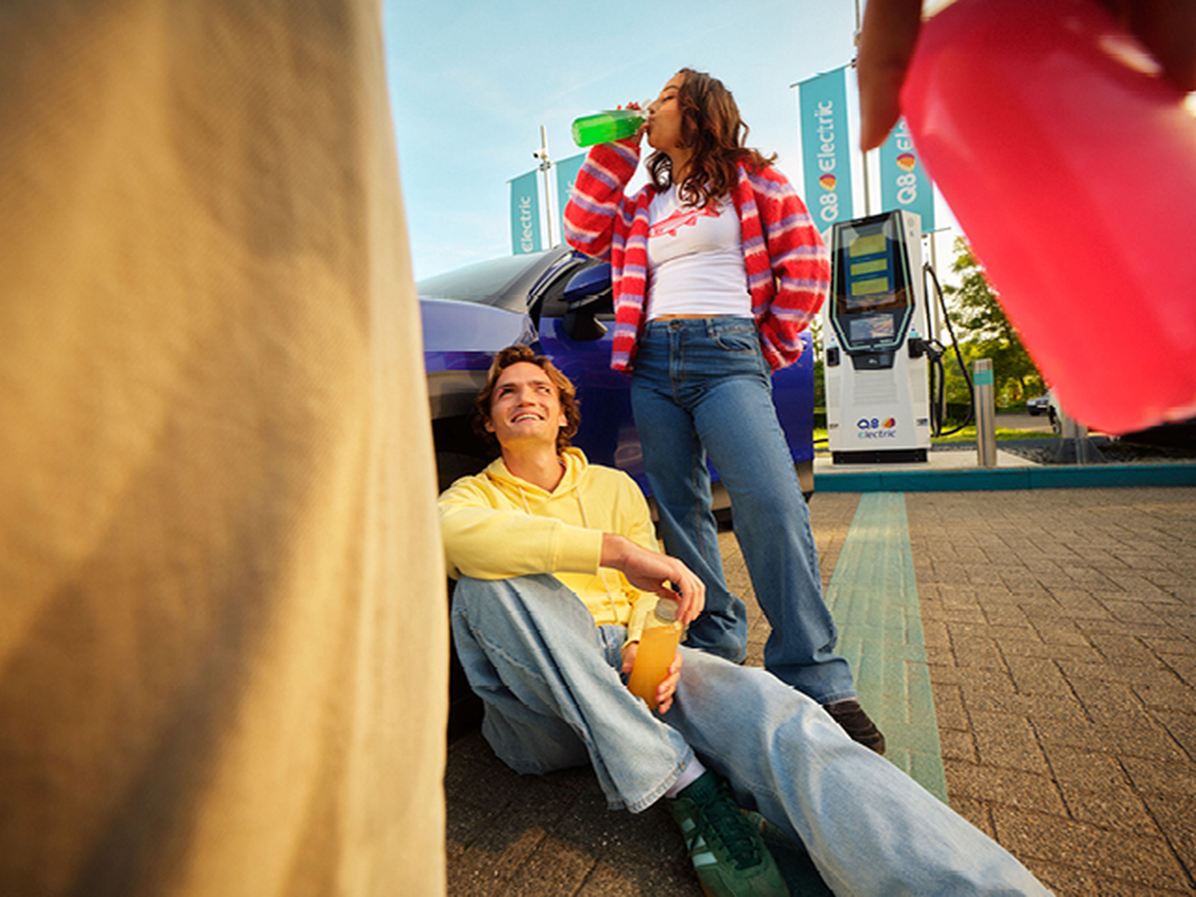 Jeunes boivent et se détendent à une station de recharge Q8 Electric.