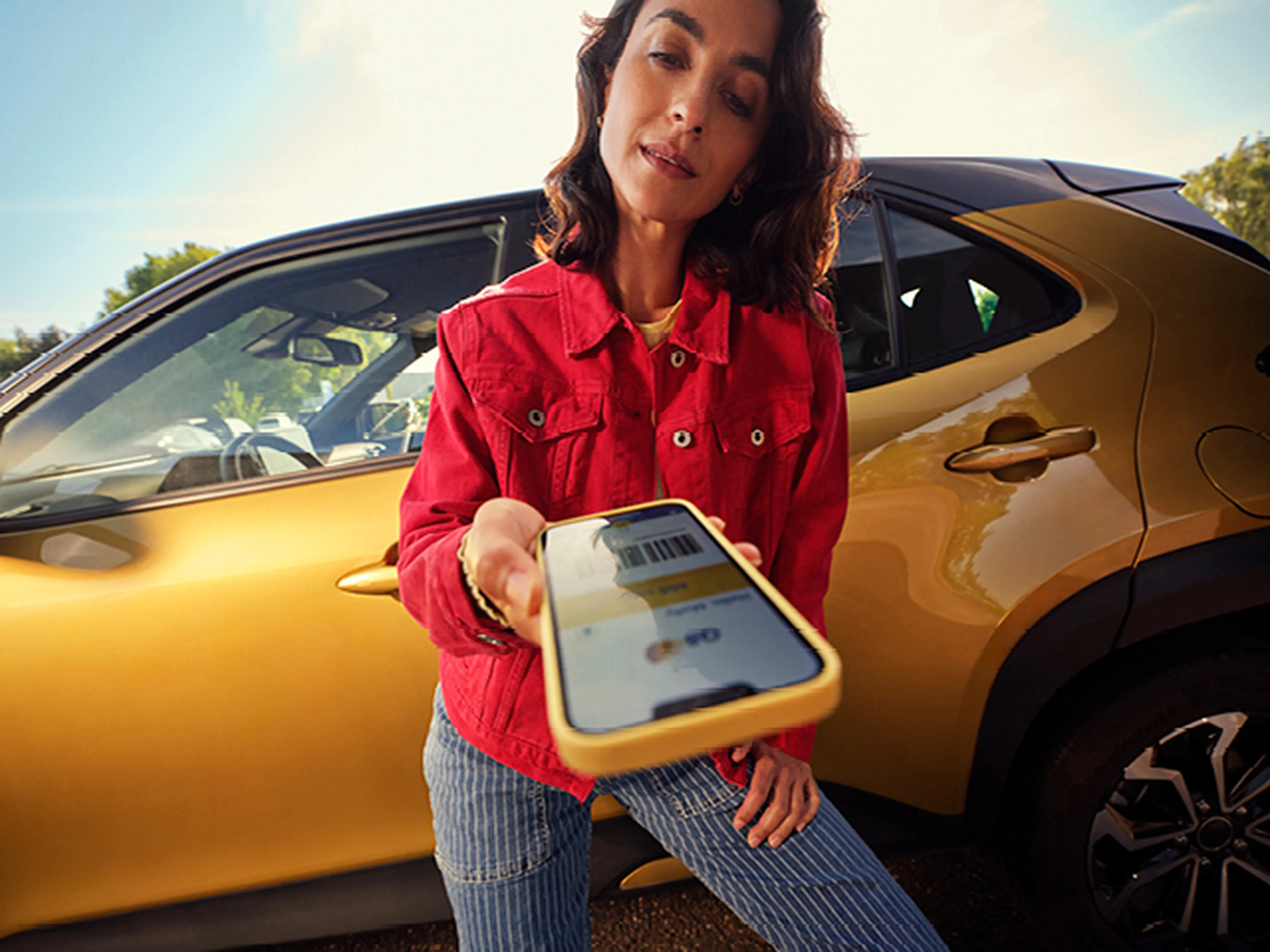 Vrouw die haar smartphone toont tijdens het opladen van haar elektrische wagen bij Q8 electric.