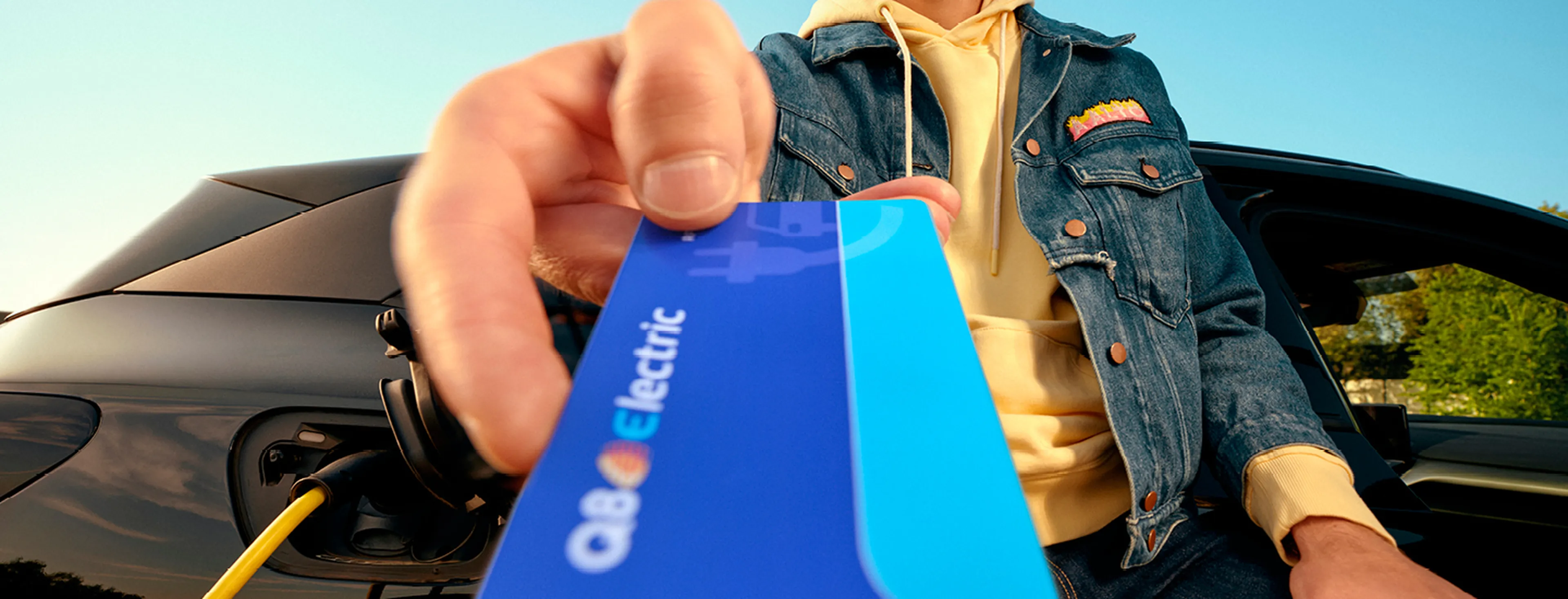 Homme montre une carte de recharge Q8 Electric près de sa voiture électrique chez Q8.​