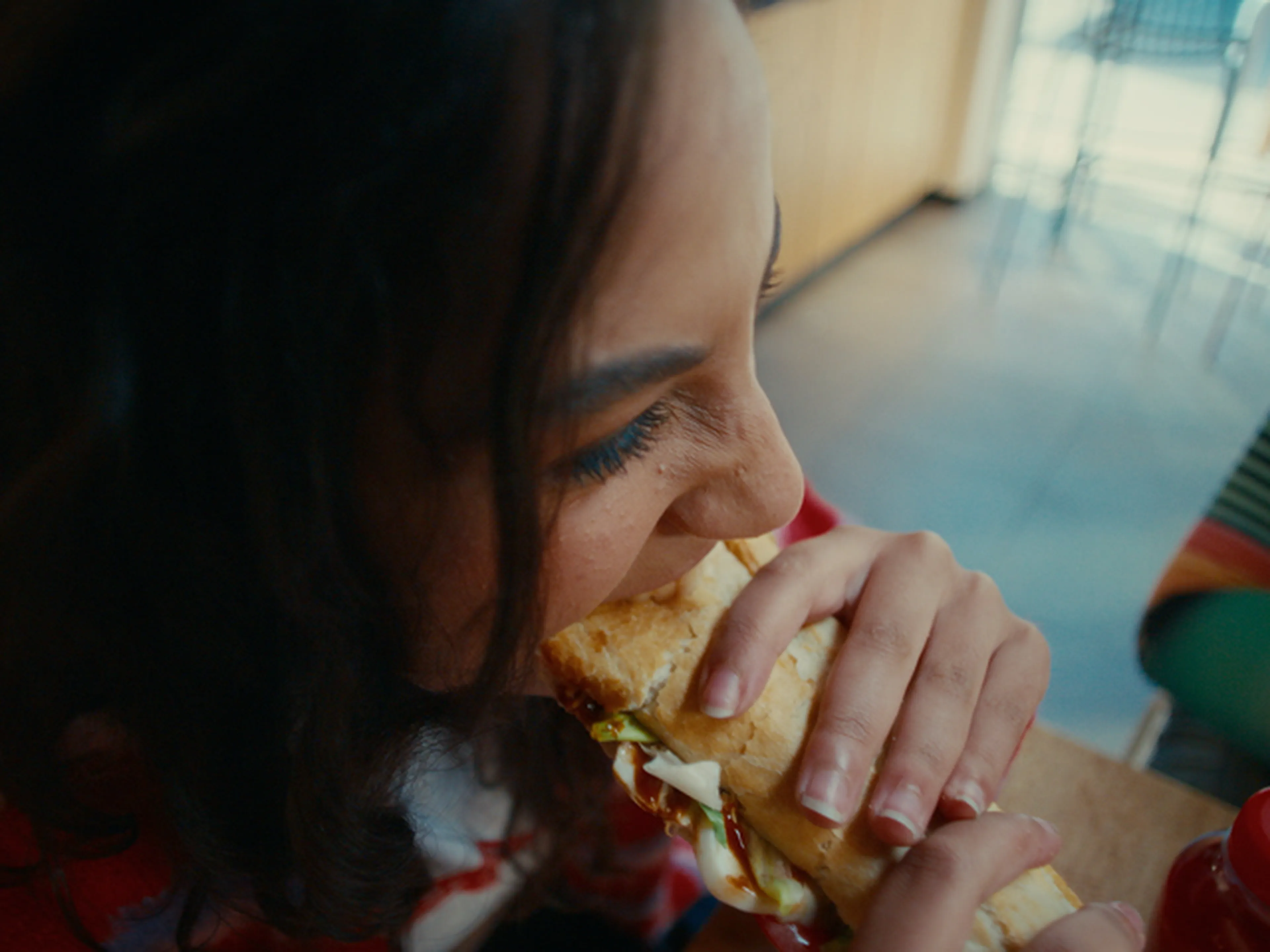 Femme croque dans un sandwich Panos dans une station Q8