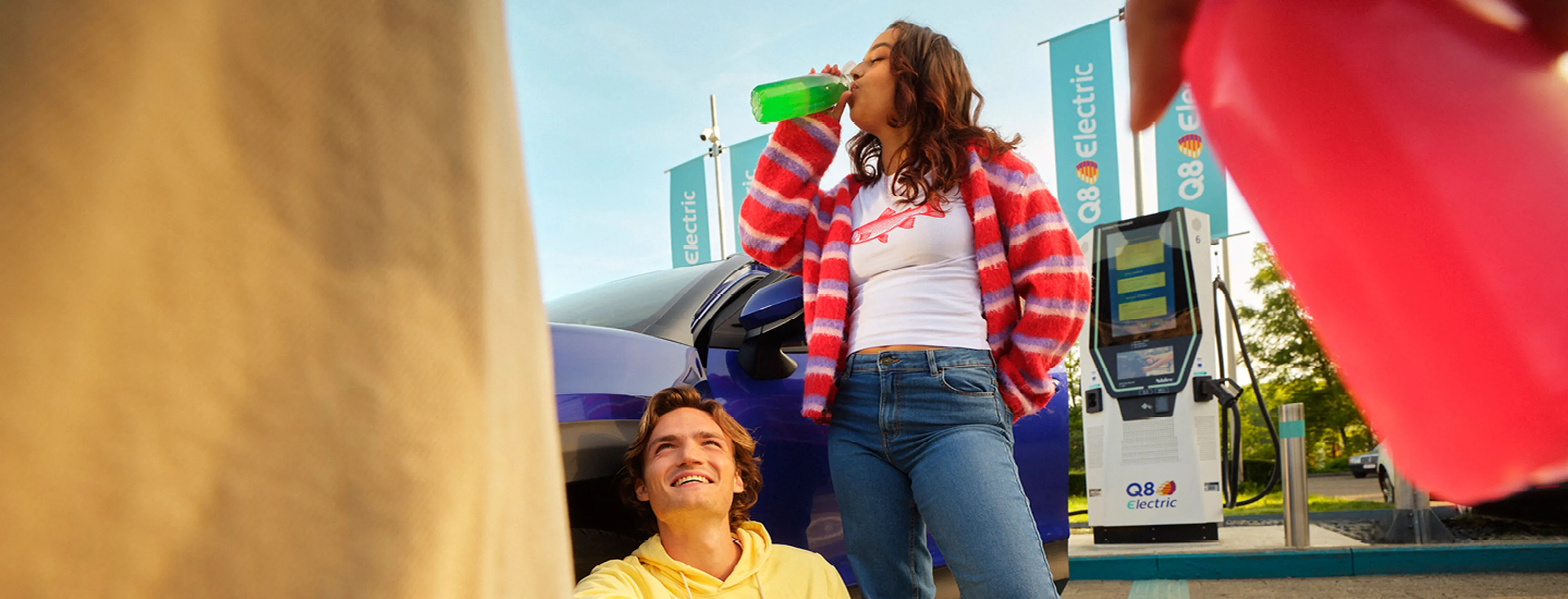 Jeunes boivent et se détendent à une station de recharge Q8 Electric.